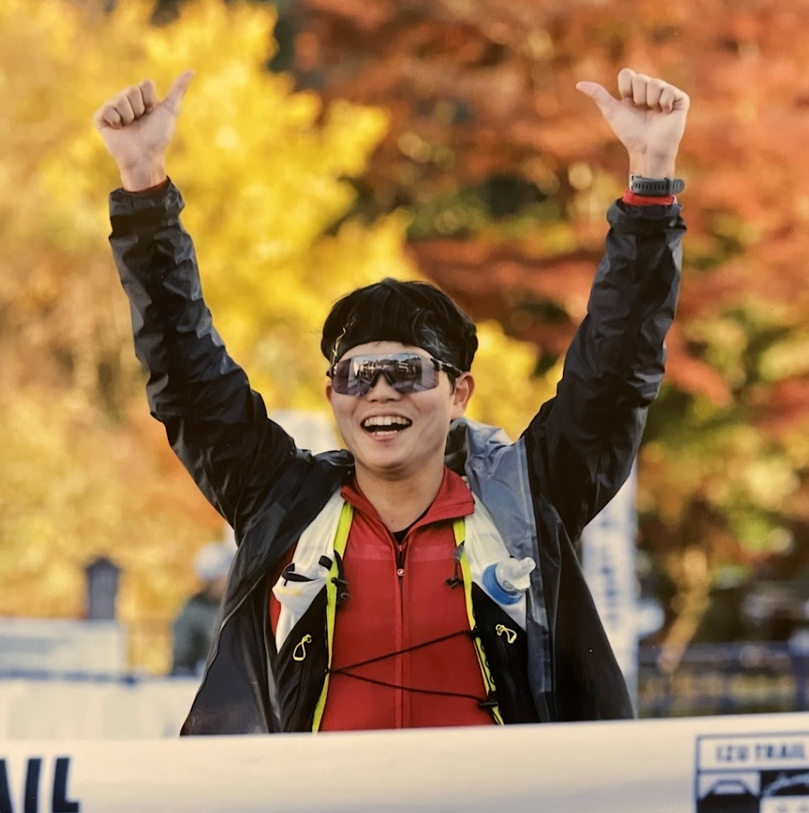秋の紅葉をバックに両手を挙げて喜ぶランナーの姿